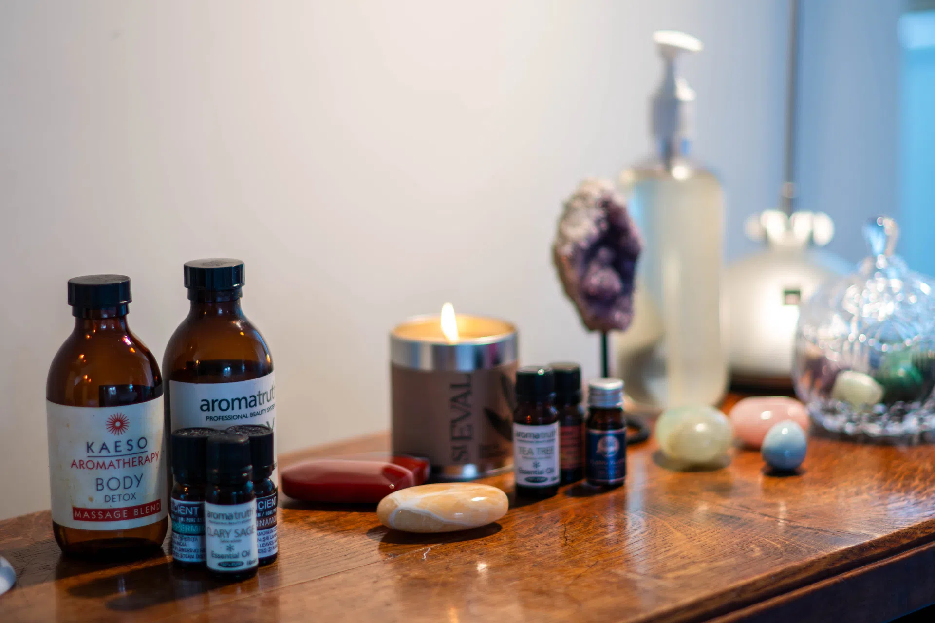Massage oil and essential oil bottles beside a lit candle.