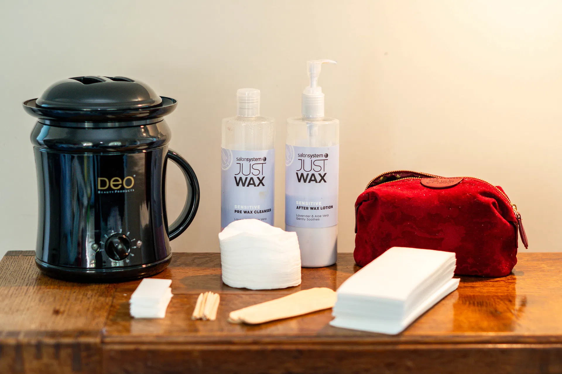 Wax heater, waxing lotions, cotton pads and wooden spatulas.